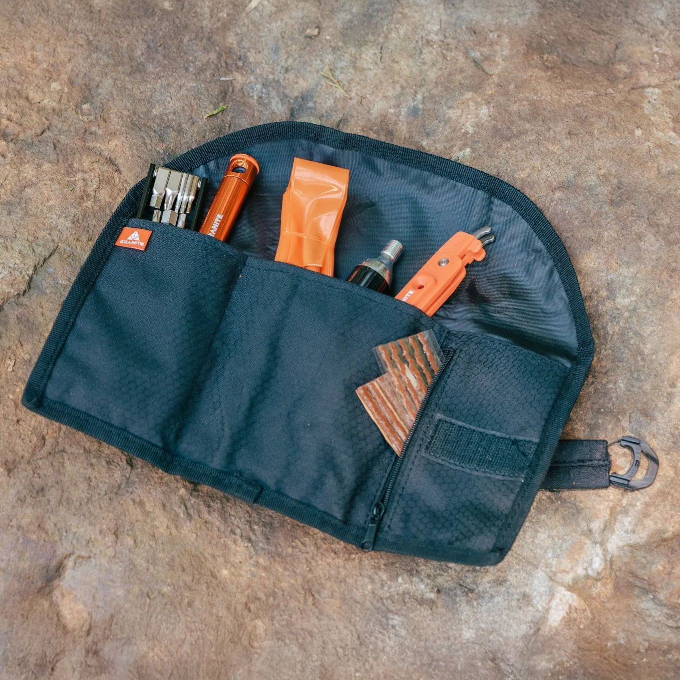 Black tool pouch with orange Granite Diverse 10 multi tools on a stone surface
