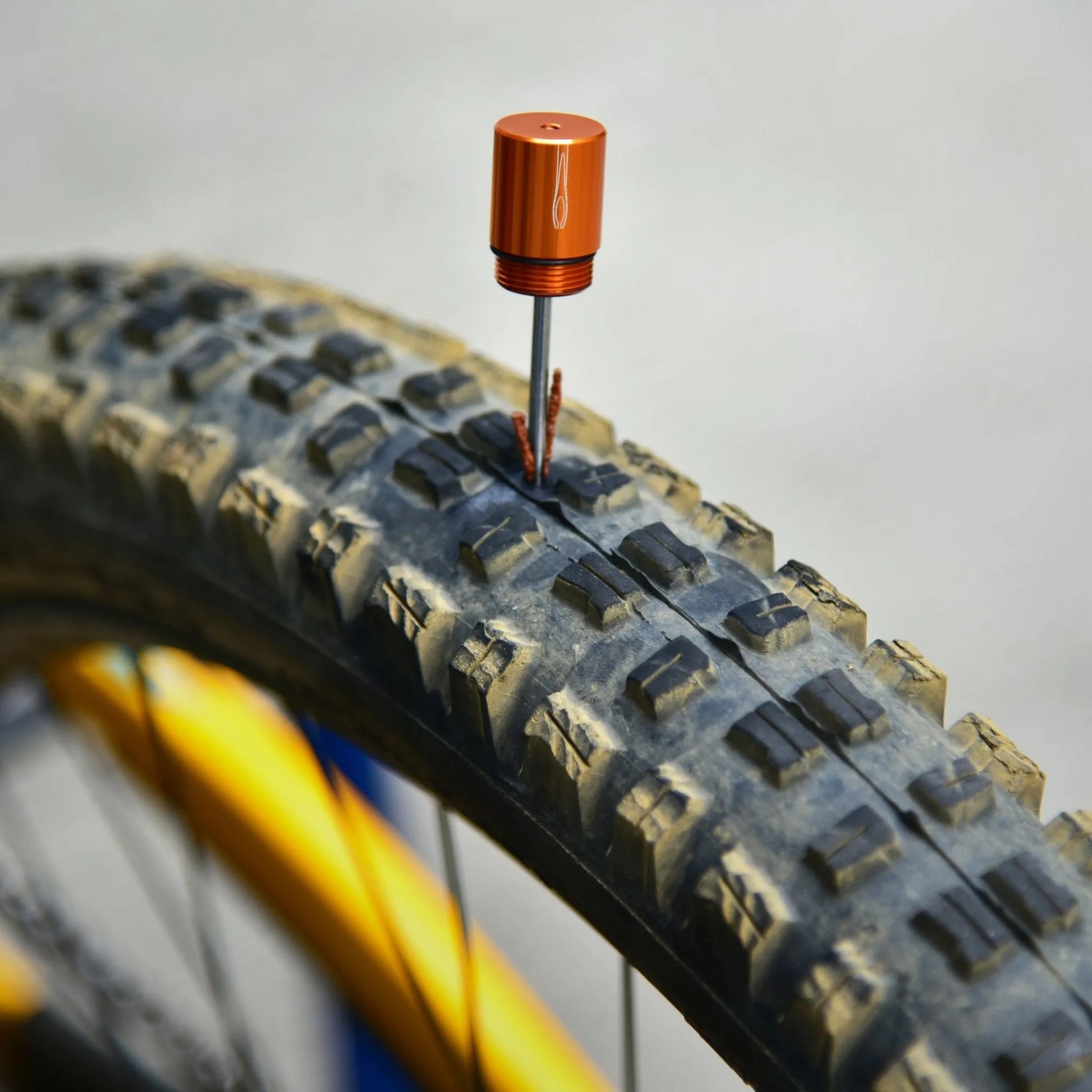 Granite Stash Tubeless Flat Tire Repair Kit inserted into a bike tire to repair a puncture, with plug strip sealing the hole.
