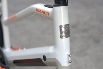 Close-up of a bicycle frame with 'WANDR' branding on a blurred background